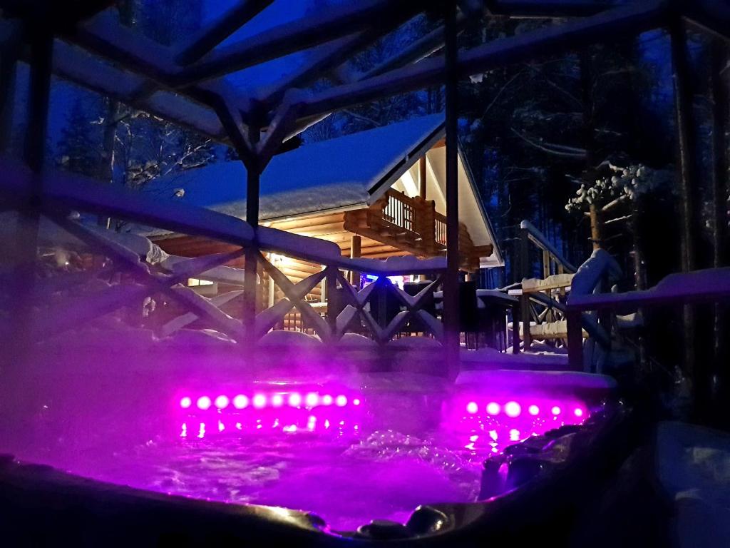 uma banheira de hidromassagem iluminada com luzes cor-de-rosa à noite em Villa Ainola em Sapsalampi