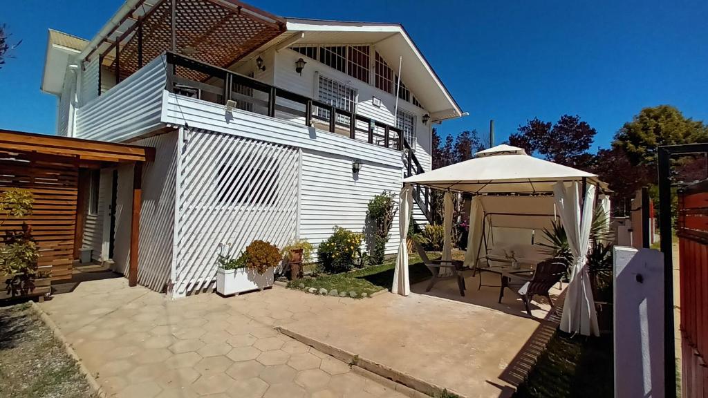 ein weißes Haus mit einem Sonnenschirm und einer Terrasse in der Unterkunft Casa hospedaje Algarrobo-El Canelo in Algarrobo