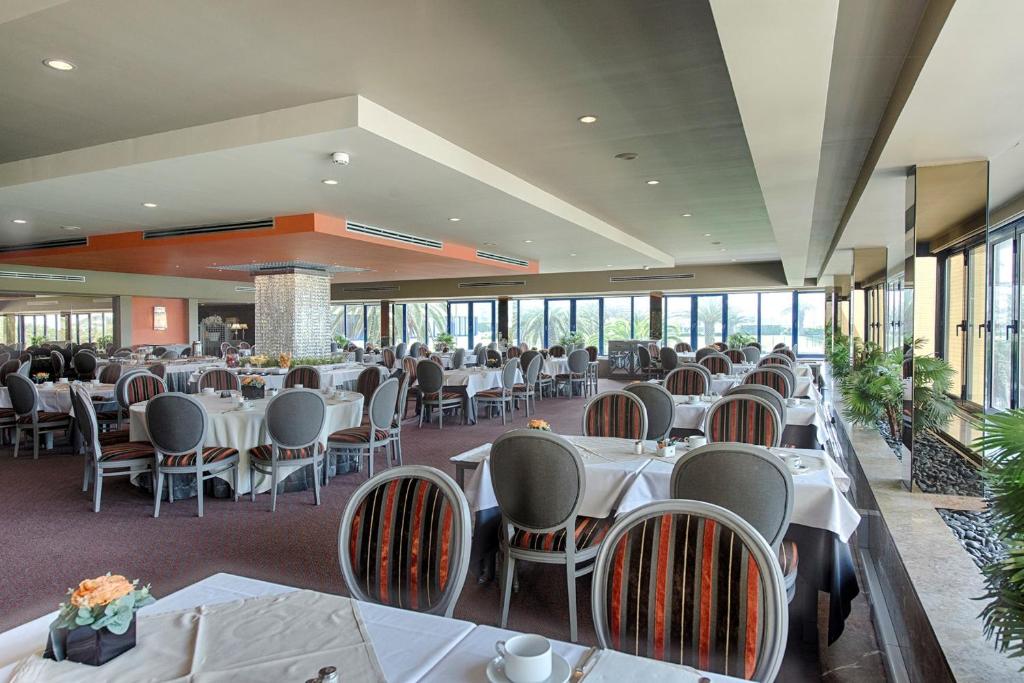 a restaurant with white tables and chairs and windows at Hotel Solverde Spa and Wellness Center in Vila Nova de Gaia