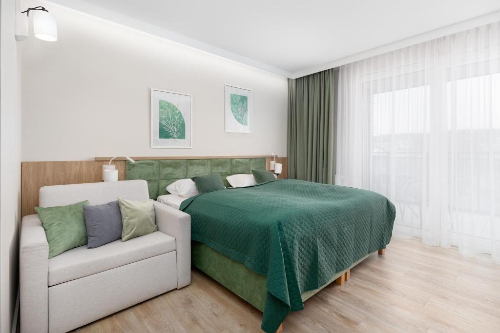 um quarto com uma cama verde e um sofá em Bel Mare Green Leaf Studio with Balcony by Renters em Międzyzdroje