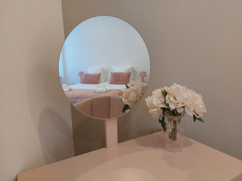 un miroir sur une table avec un vase de fleurs dans l'établissement Le Bag Centre ville, à Colmar