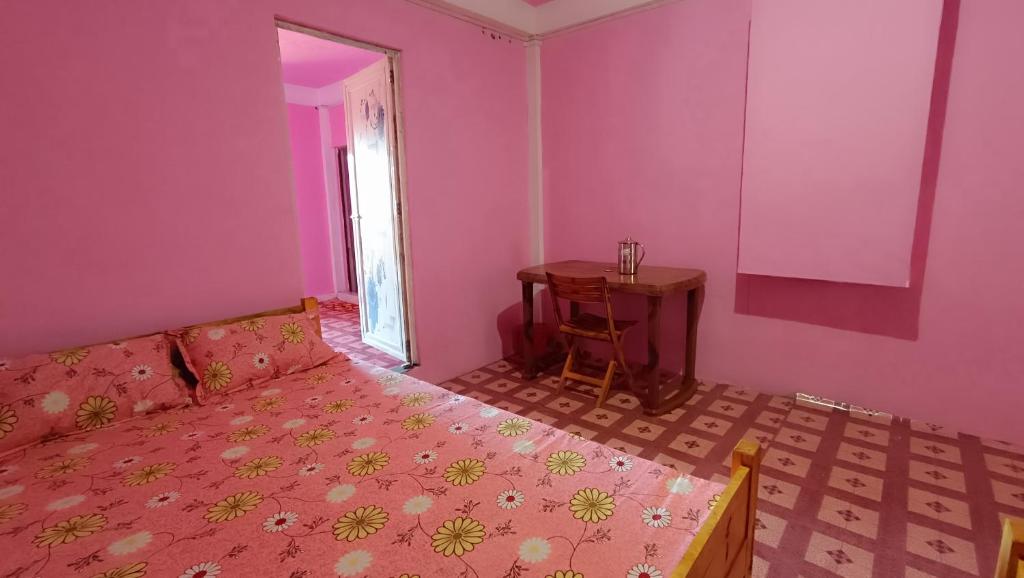 a pink room with a bed and a table at PAMILYA HOMESTAY in Cherrapunji