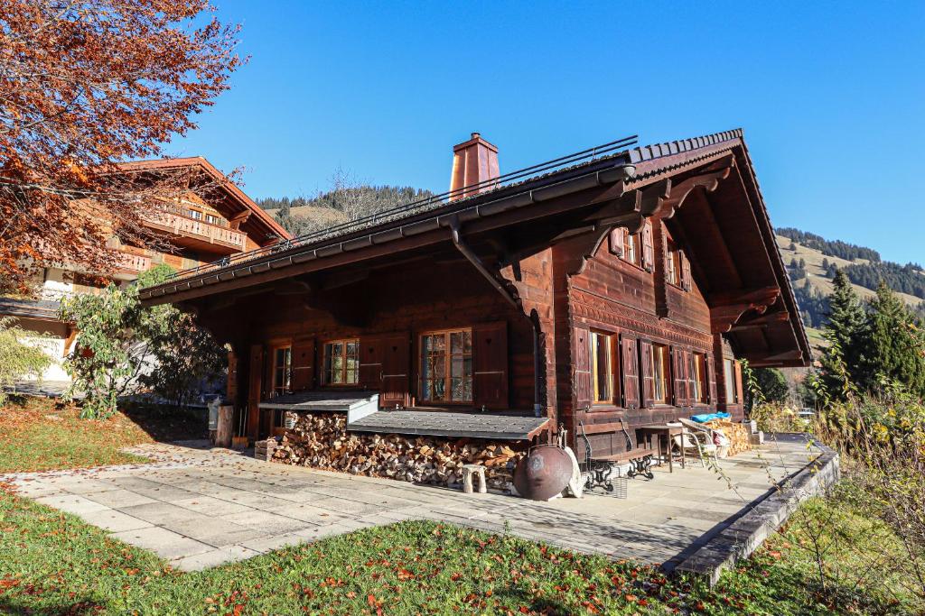 a large wooden house with a porch and dogs outside at Les Jumelles in Gstaad