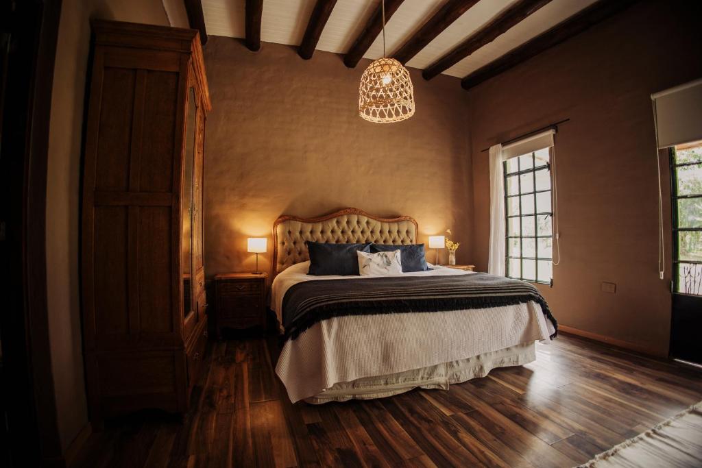 1 dormitorio con cama y lámpara de araña en El Pinar de La Caballeriza en San Rafael