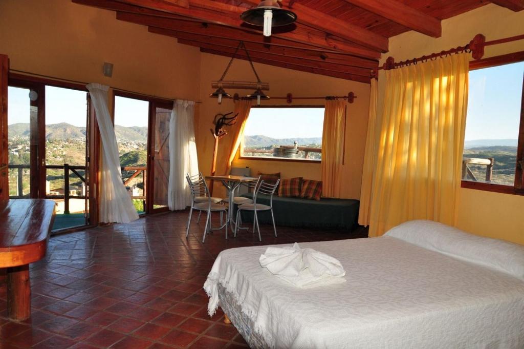 Schlafzimmer mit einem Bett, einem Tisch und Stühlen in der Unterkunft Cabañas Terrazas del Sol in Villa Carlos Paz