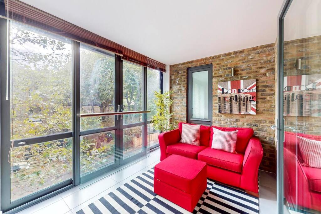 uma sala de estar com mobiliário vermelho e janelas grandes em Stunning 2 Bed Apartment with view of the Shard em Londres