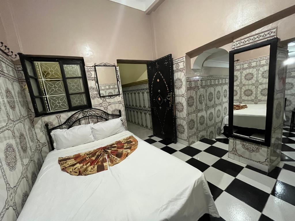 a bedroom with a bed and a checkered floor at Hotel Zagora in Marrakesh