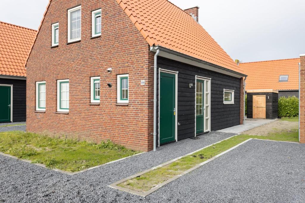 にあるHello Zeeland - Vakantiewoning Knuitershoek 104の緑の扉が横に並ぶレンガ造り