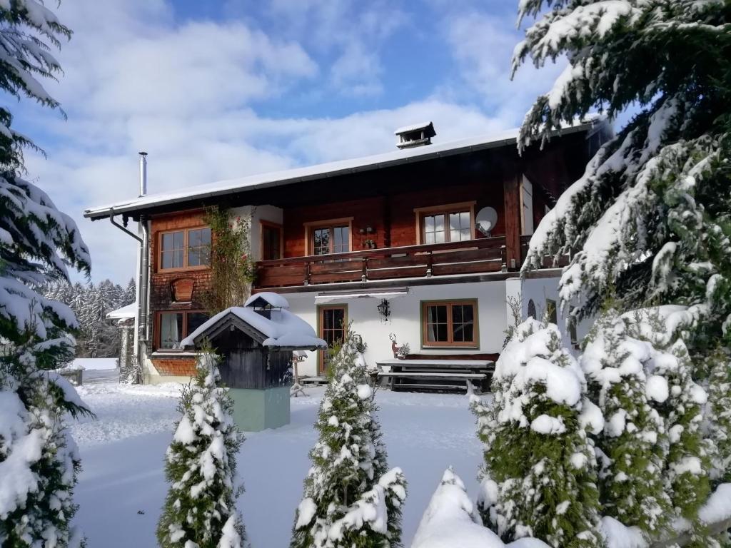 een huis in de sneeuw met sneeuw bedekte bomen bij Ferienwohnung zum Gimpei in Siegsdorf