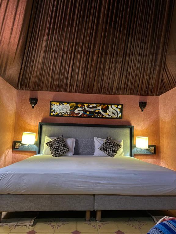 a bedroom with a large bed with two lamps at Panorama Complex in Tahannout