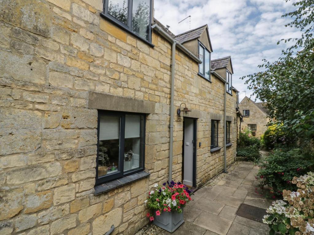 a stone building with windows and flowers on the side at The Cottage in Chipping Campden
