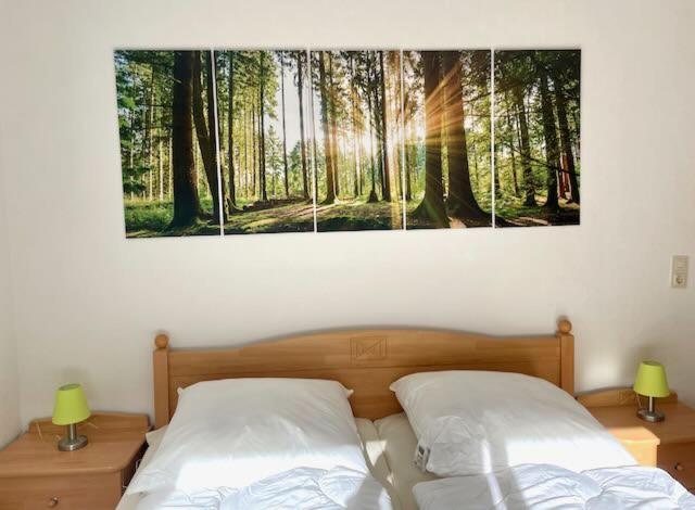 een slaapkamer met 2 bedden en een schilderij van een bos bij Ferienwohnung Carpe Diem in Bad Harzburg