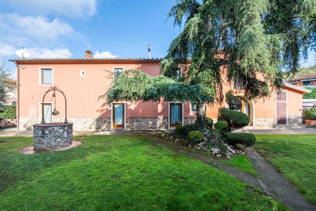 a house with a large tree in the yard at La Bella Toscana Ulivo Apartment in Monsummano Terme