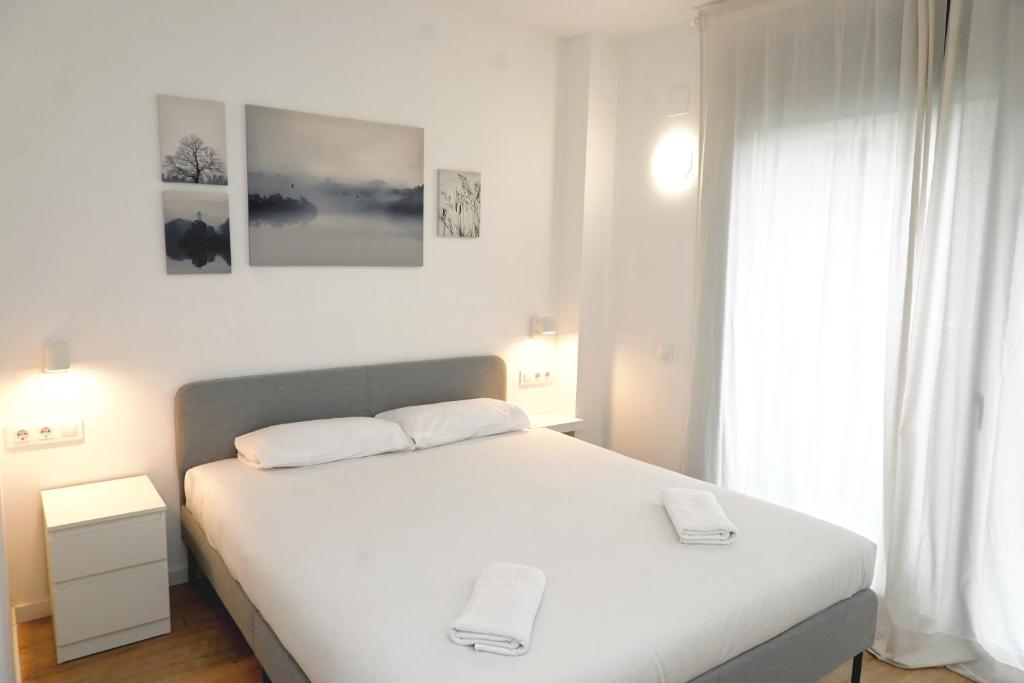 a bedroom with a white bed and a window at Homenfun Barcelona Can Serra in Hospitalet de Llobregat