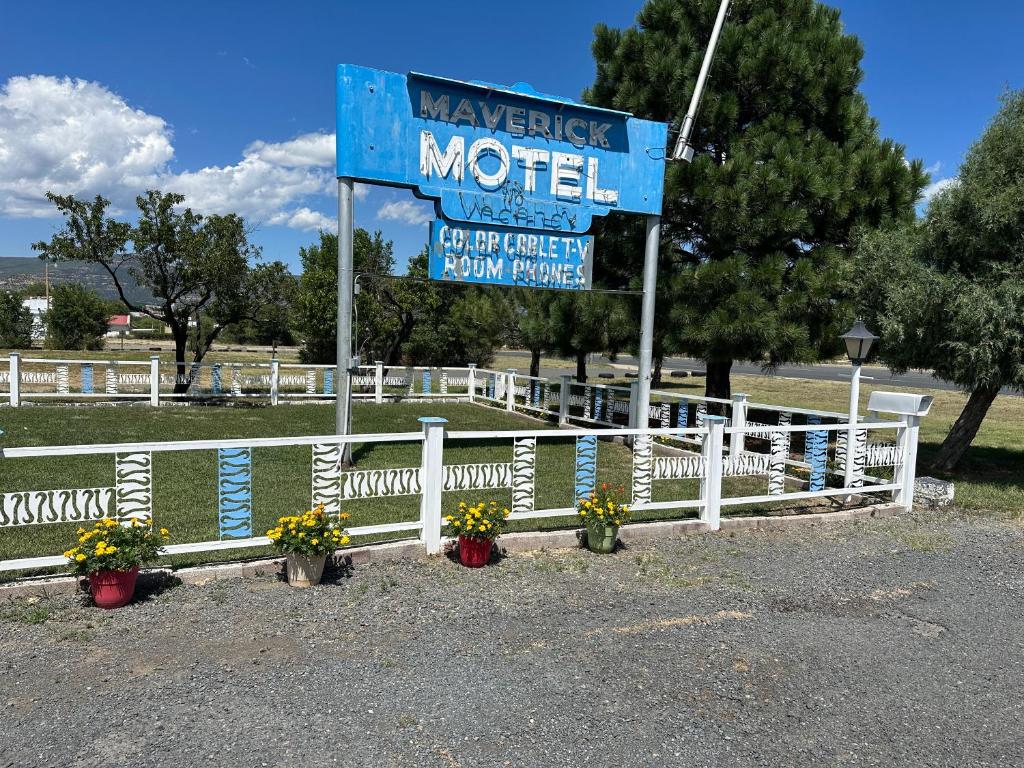una señal para un motel junto a una cerca blanca en Maverick Motel, en Ratón