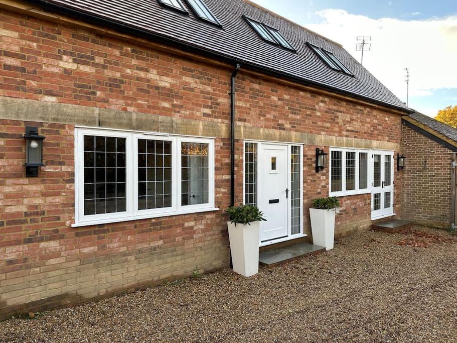 a brick building with white doors and potted plants at Stylish Surrey Hills House 2 ensuite bedrooms in Ockley