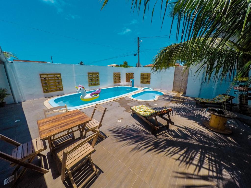 un patio con una piscina con bancos y una mesa en Barra Grande Pousada en Maragogi