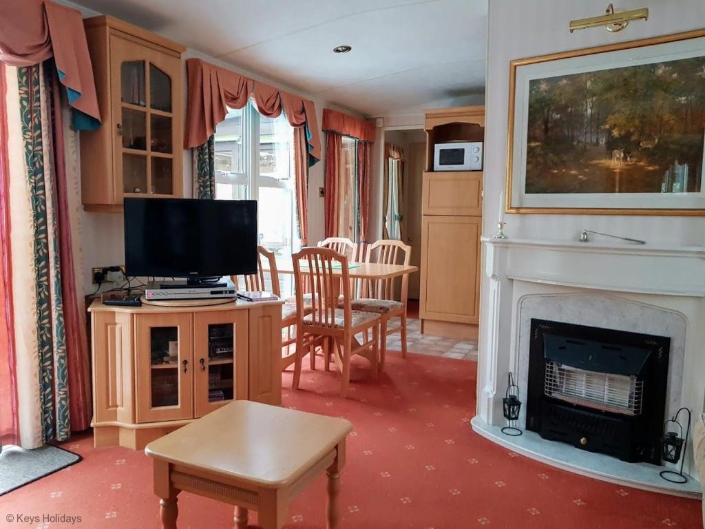 a living room with a tv and a fireplace at Green Shores in Weybourne