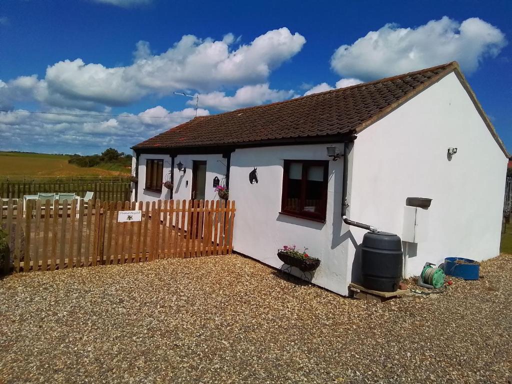 a small white house with a wooden fence at Paddock Bungalow in Mundesley