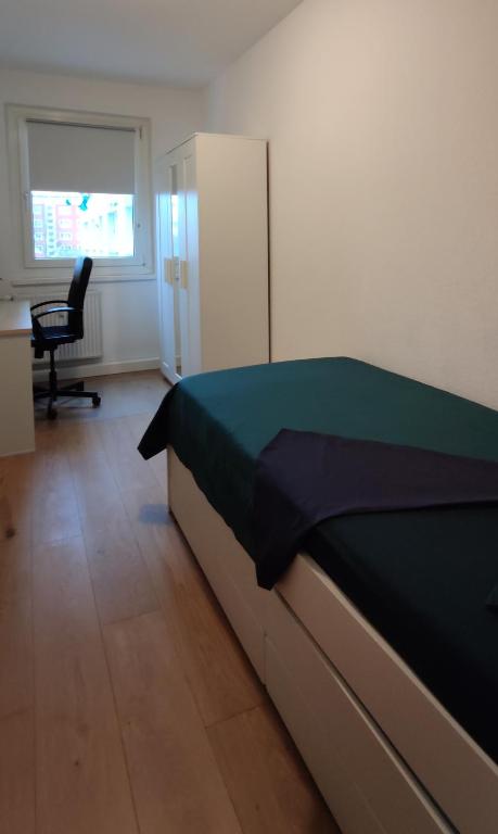 1 dormitorio con cama, escritorio y silla en Komfortables und sauberes Zimmer en Leipzig