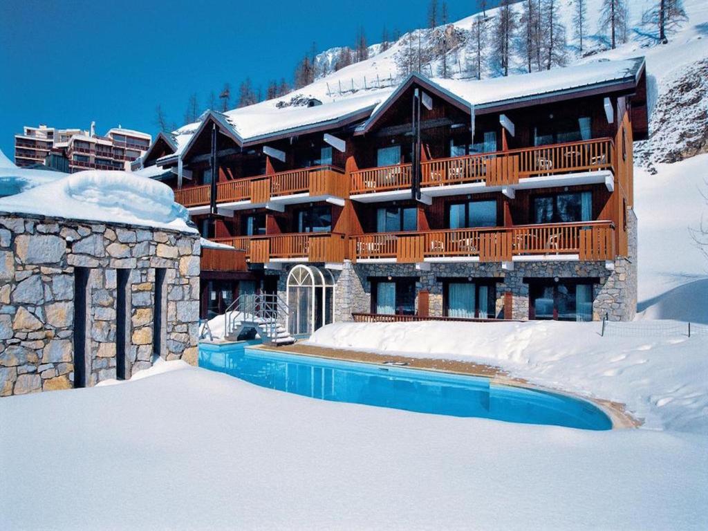 a large building in the snow with a swimming pool at Residence & Spa Les Chalets de Solaise in Val-d'Isère