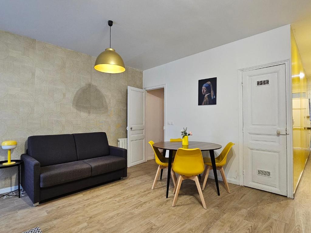 sala de estar con sofá, mesa y sillas en Petite maison proche du métro, en Bagnolet