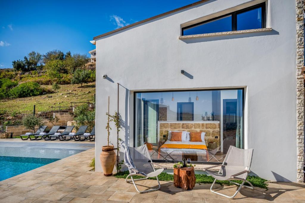 a white house with a pool and chairs at Villa Pharus Scopello in Scopello