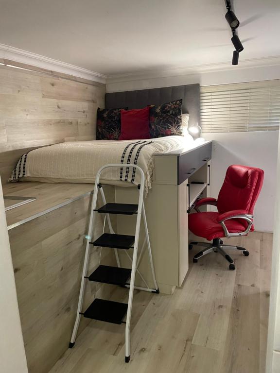 een slaapkamer met een bed, een bureau en een stoel bij Church Road Apartment in Port Elizabeth