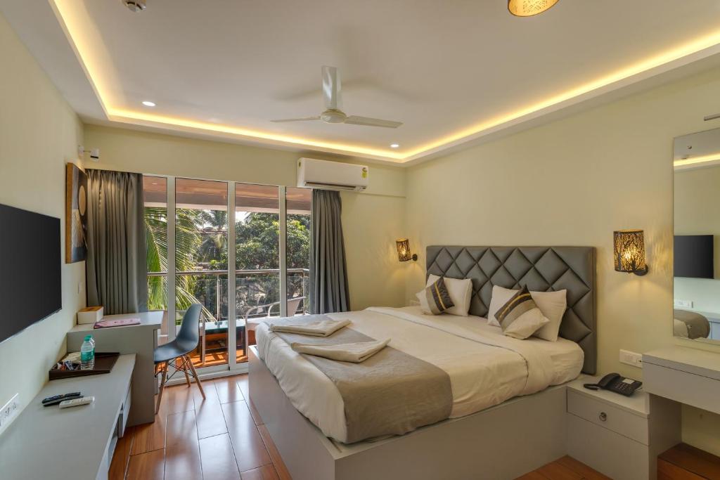 a bedroom with a bed and a desk and a window at La baga Beach Hotel By Orion Hotels in Calangute