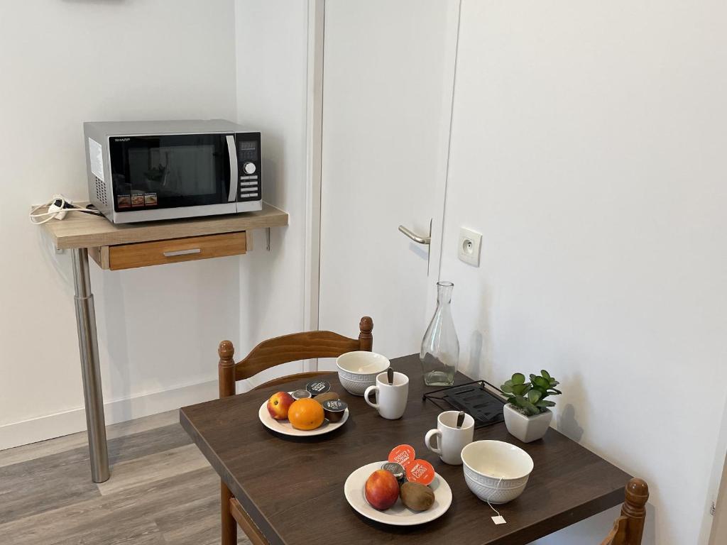 a table with plates of fruit on top of a microwave at Studio Aix-les-Bains, 1 pièce, 2 personnes - FR-1-617-23 in Aix-les-Bains