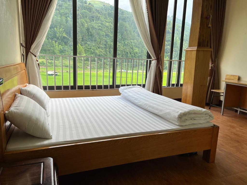 a bed in a room with a large window at Homestay Hoà Thảo in Mù Cang Chải