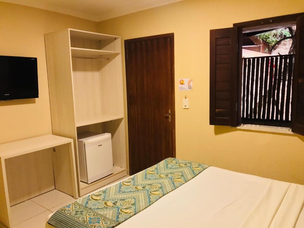 a small bedroom with a bed and a window and a window at Hotel Pousada Latitude in Canoa Quebrada