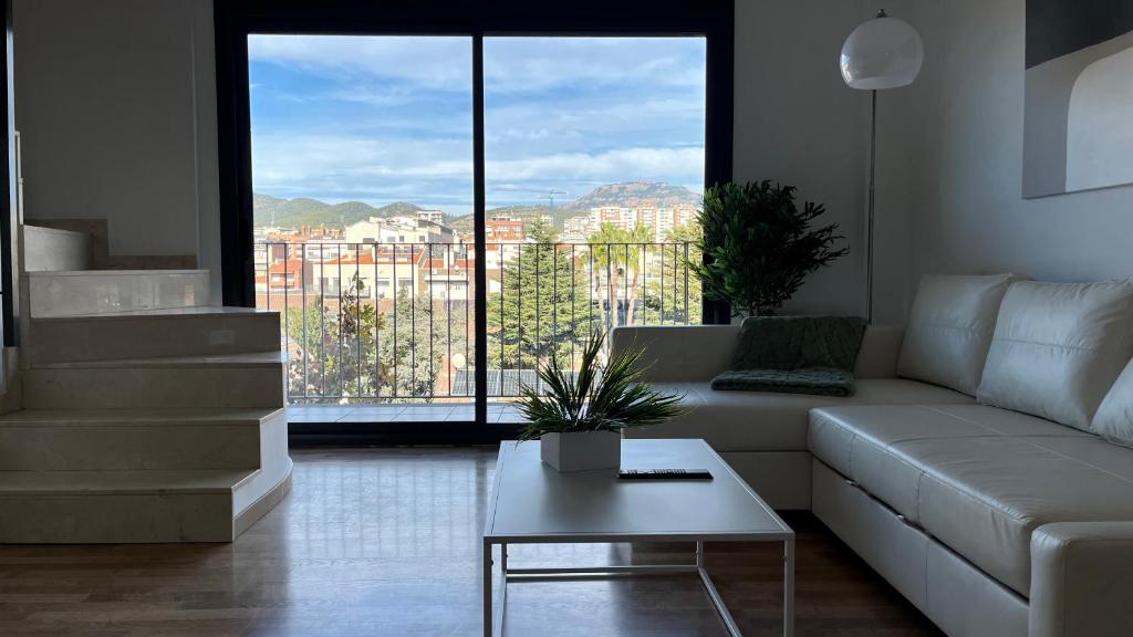 een woonkamer met een witte bank en een tafel bij Dúplex con terraza by Prestigi in Terrassa