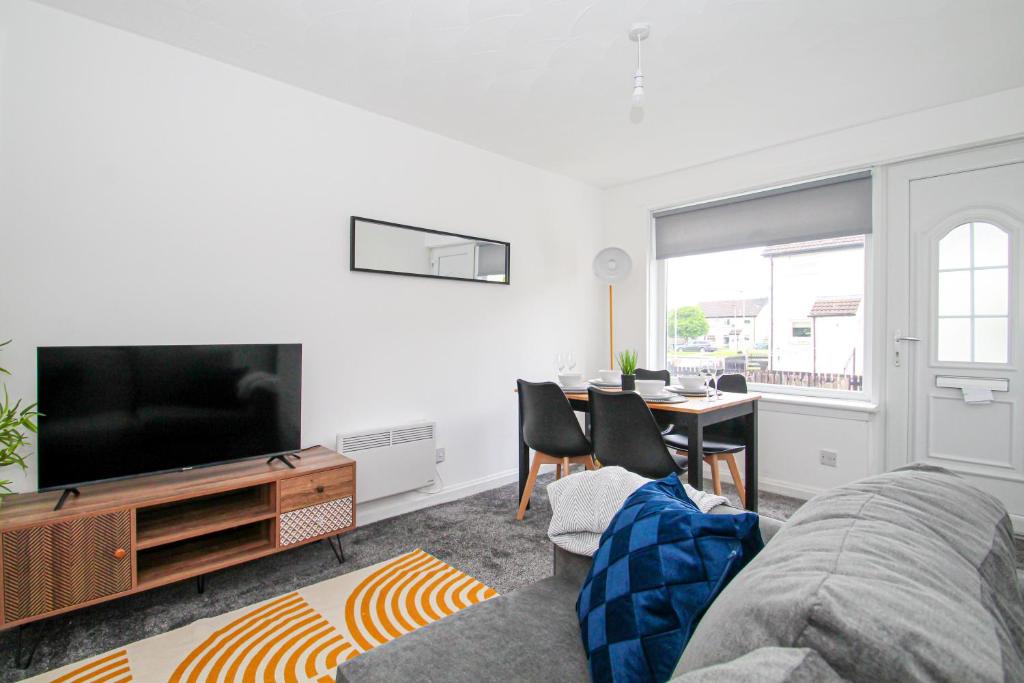 a living room with a couch and a tv and a table at Greenside Getaway in Newarthill