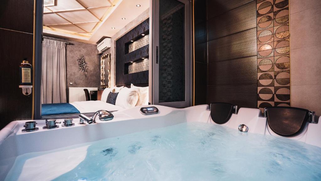 a bathroom with a tub with a bed and a mirror at Eliton Hotel & Spa in Kato Loutraki