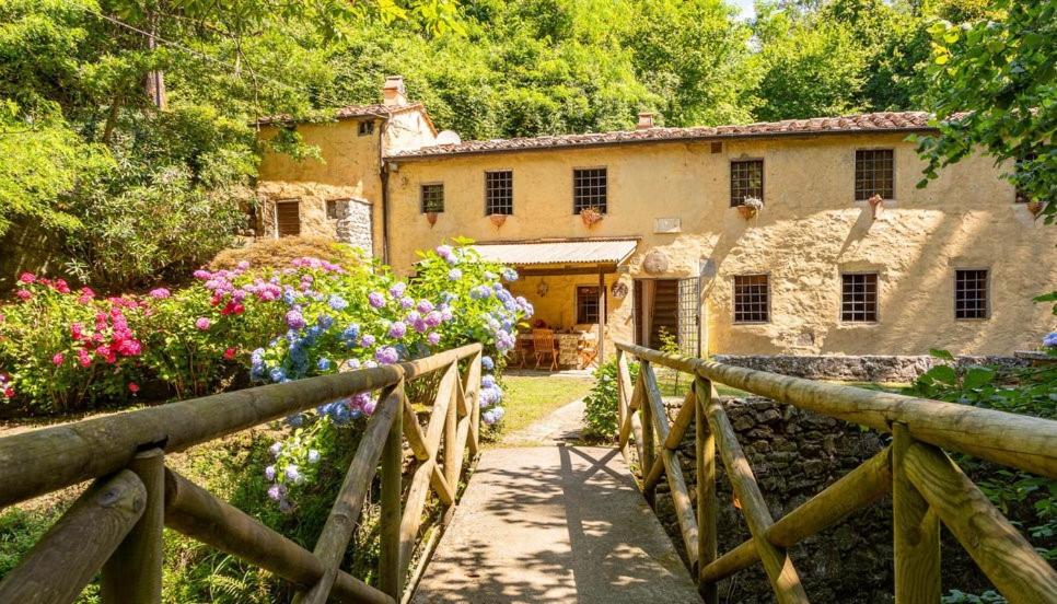 una vecchia casa con una recinzione in legno e fiori di Molin Barletta - Nice Holiday House With Private Pool Marliana, Toscana a Marliana
