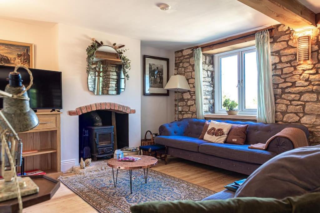 a living room with a blue couch and a fireplace at Lovely 2 BD with stunning views over Stroud valley 