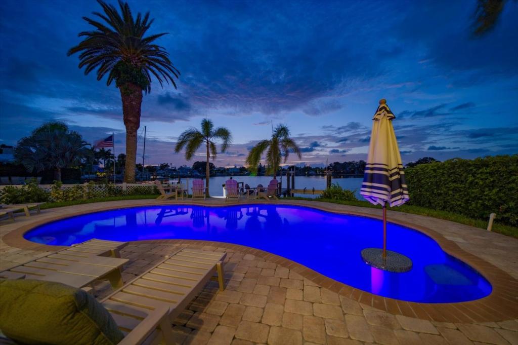 una piscina con sombrilla y palmera en Waterfront Luxury w/ Heated Salt Pool & Golf Cart en Clearwater Beach