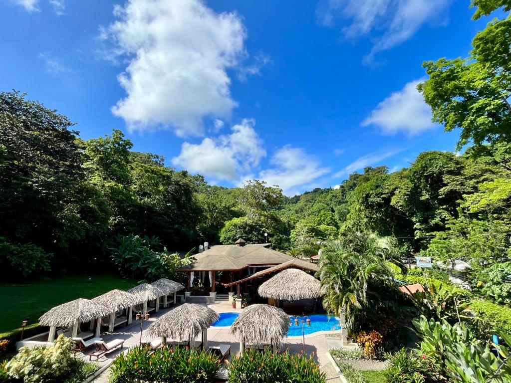 a resort with a pool and straw umbrellas at Hotel Playa Espadilla & Gardens in Manuel Antonio