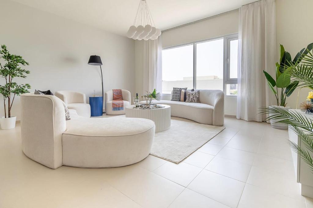 uma sala de estar branca com mobiliário e plantas brancas em Frank Porter - Urbana 3 no Dubai