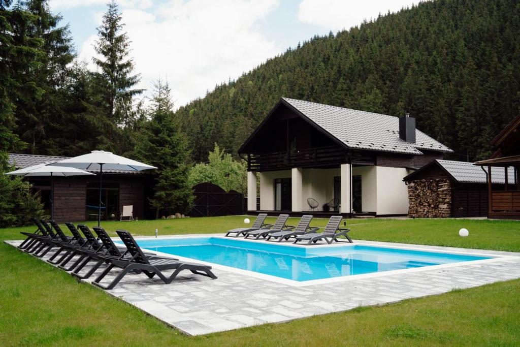 a swimming pool with lounge chairs and a house at Berghaus Bukovel in Bukovel