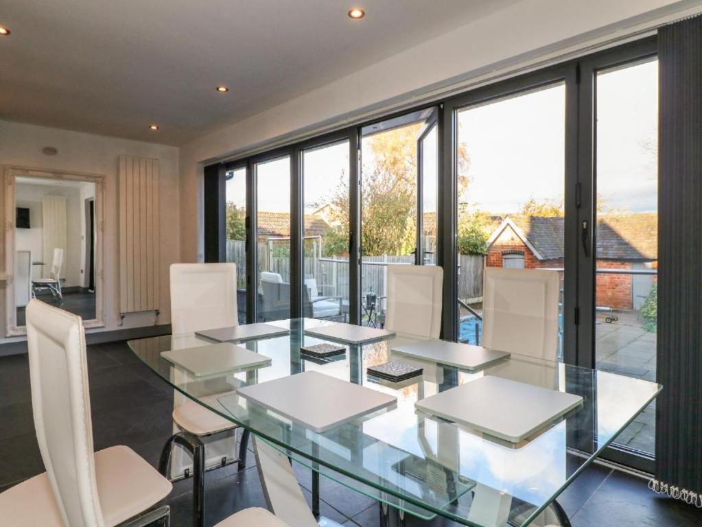 a dining room with a glass table and white chairs at Beautiful Holiday Home Village Sleeps up to 6 in West Hallam