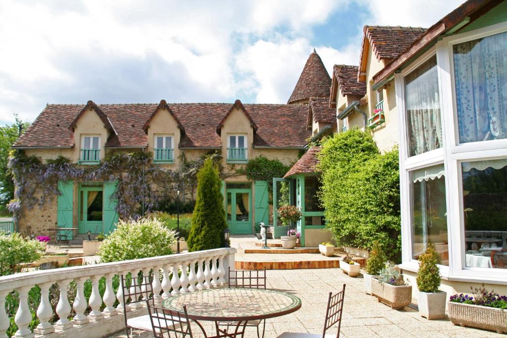 a courtyard of a house with chairs and a table at Les Etangs de Guibert in Neufchâtel-en-Saosnois