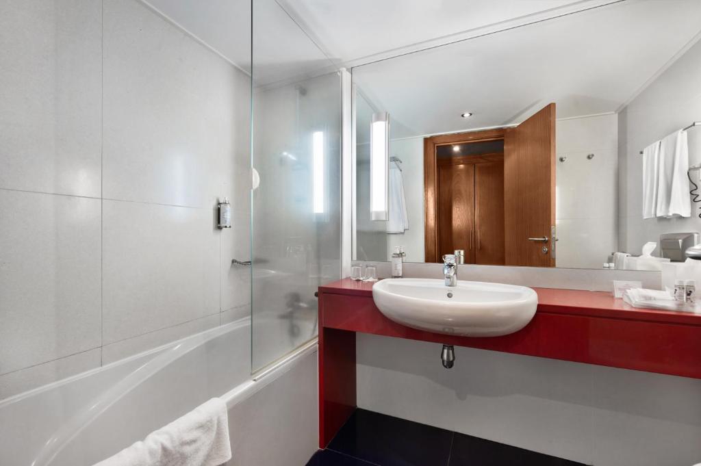 a white bathroom with a sink and a mirror at Hotel Do Caracol in Angra do Heroísmo