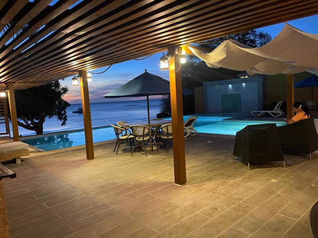 a patio with a table and an umbrella and a pool at Hotel Sand Bay in Punta Rucia