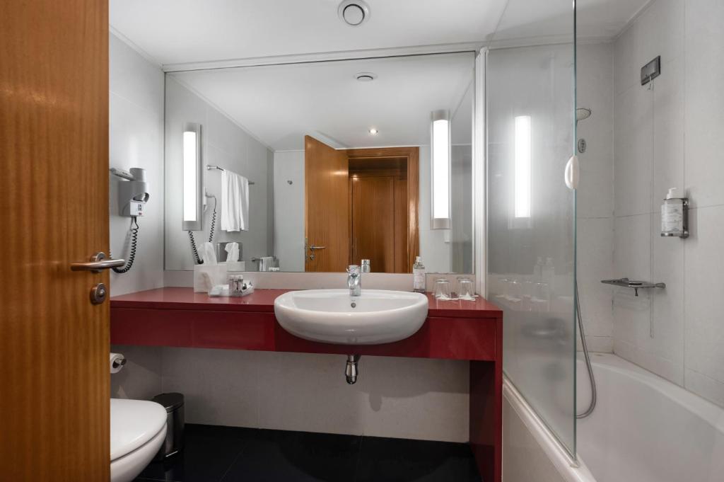 a bathroom with a sink and a shower and a mirror at Hotel Do Caracol in Angra do Heroísmo