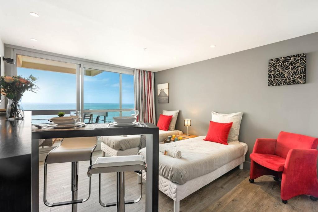 Una sala de estar con una cama, una mesa y sillas. en Biarritz - Residence Victoria surf - Face océan, en Biarritz