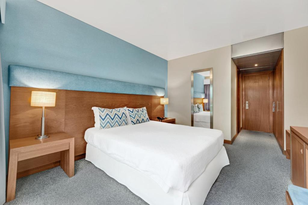 a bedroom with a white bed and a blue wall at Hotel Do Caracol in Angra do Heroísmo