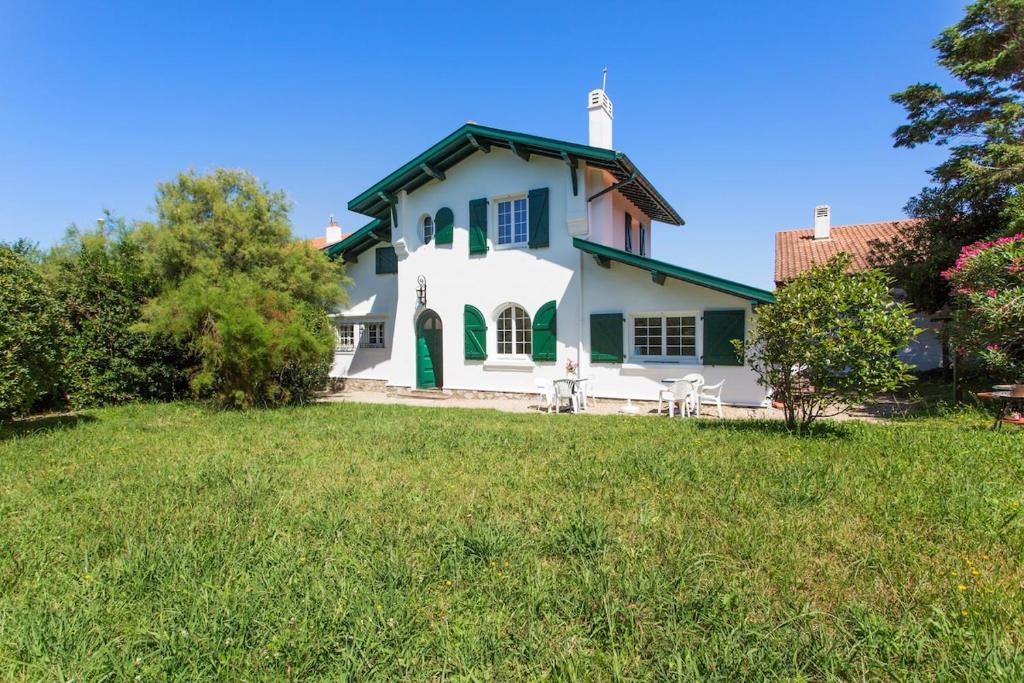 a white house with green trim on a green lawn at Bidart - Uhabia plage - Maison familiale in Bidart