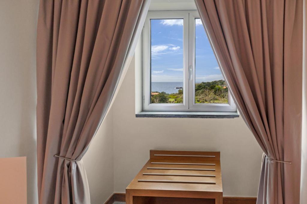 a room with a window with curtains and a bench at Hotel Do Caracol in Angra do Heroísmo